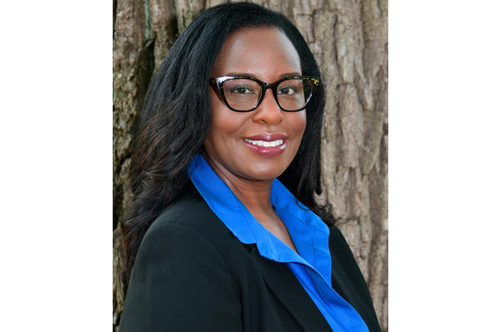 headshot of woman outside in black blazer, blue collared shirt and glasses