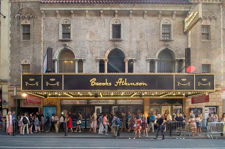 Broadway theater with black awning reading Brooks Atkinson in lights