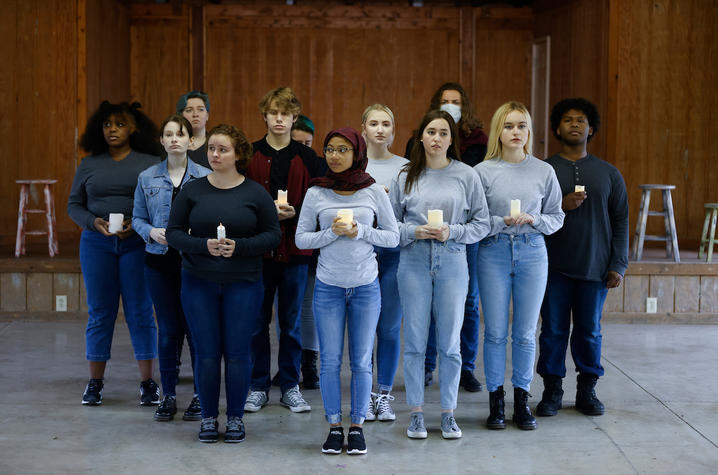 theater students standing and holding candles in triangle shape