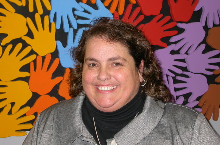 headshot of smiling woman with colorful handprints in background
