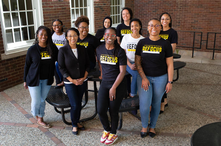10 women of color in t-shirts that say REFOCUS smiling for camera