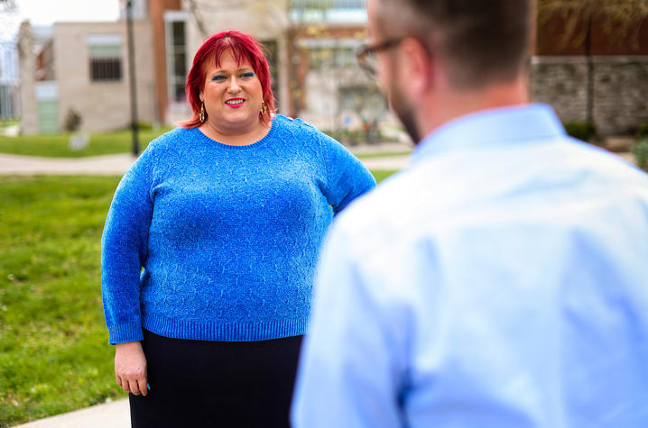 woman outside smiling in blue top while talking to man 