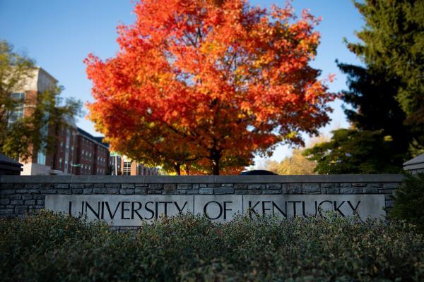 Photo of UK sign in front of colorful fall tree