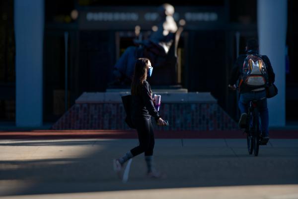 photo of student walking in front of statue