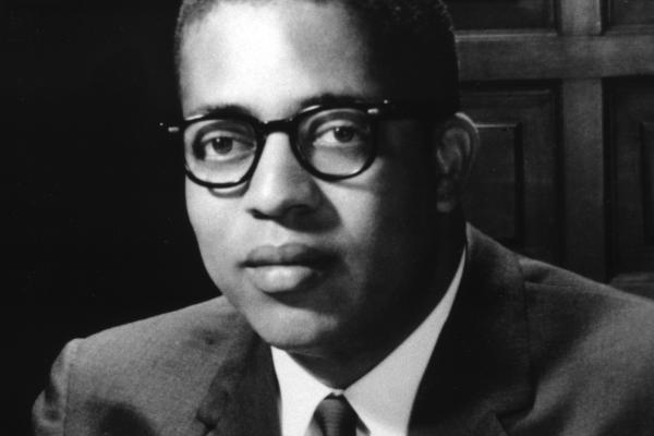 black and white image of man with glasses wearing suit and tie