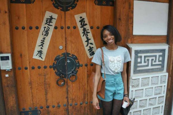 image of student traveling abroad standing in front of doors with Chinese characters 