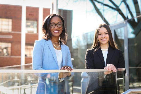 two women of color posing for photo outside