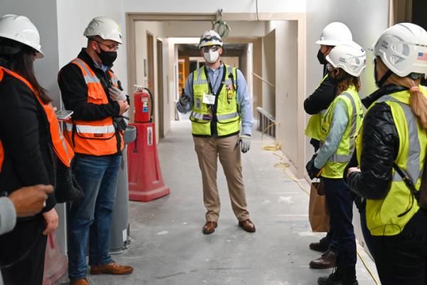 Construction workers with masks, vests and hard hats in hallways