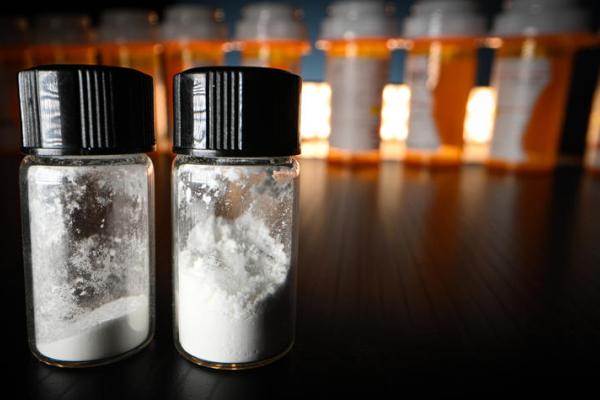 white powder in two containers with prescription bottles in the background
