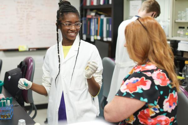 Black female student in lab coat working on research