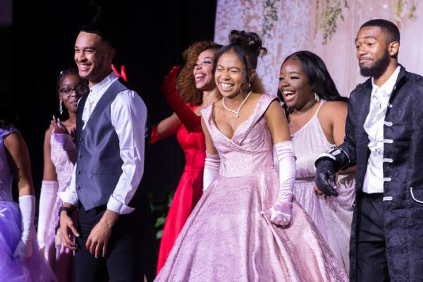 Group of Black students dress in formal attire smiling on stage