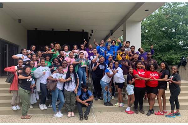 Group of Black students smiling and making sorority and fraternity signs with hands