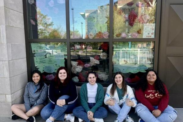 Group of female students sitting in front of window and smiling for photo