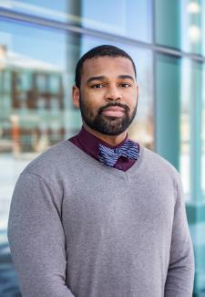 headshot of man outside in sweater and blue bowtie