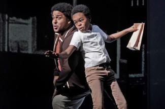 Black man acting with young black boy on stage