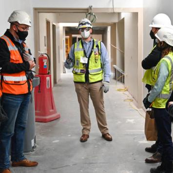 Construction workers with masks, vests and hard hats in hallways